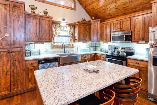 kitchen featuring light stone counters, a kitchen island, sink, and stainless steel appliances