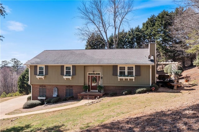 split foyer home featuring a front lawn, brick siding, driveway, and a chimney