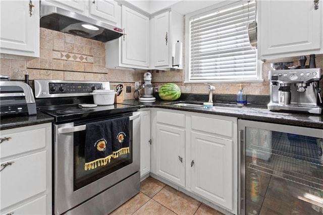 kitchen featuring stainless steel range with electric stovetop, under cabinet range hood, beverage cooler, a sink, and white cabinetry