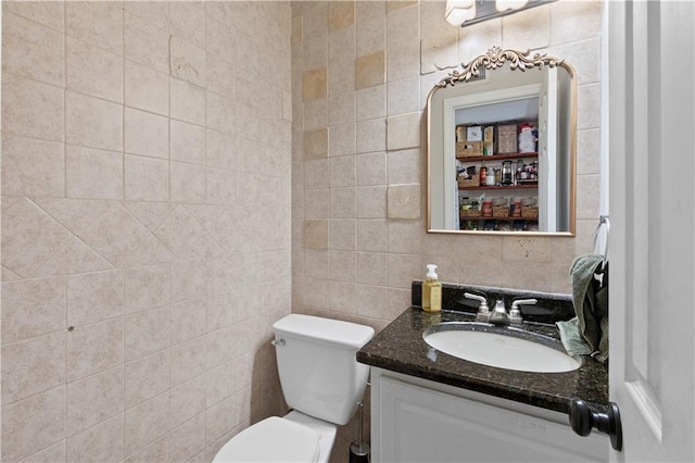 half bathroom featuring tile walls, vanity, and toilet