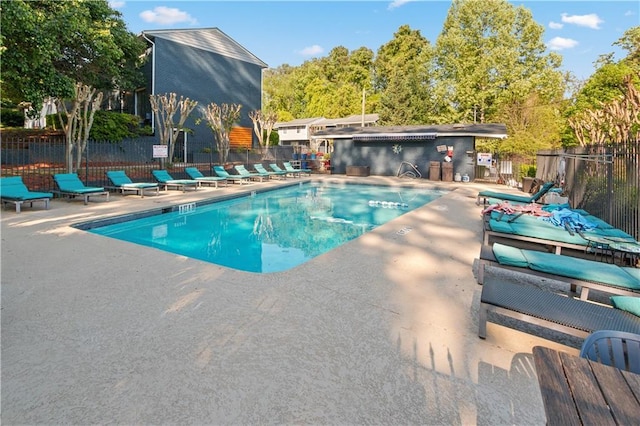 community pool with a patio area and fence