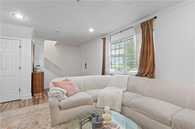 living area featuring wood finished floors, a textured ceiling, recessed lighting, crown molding, and stairs