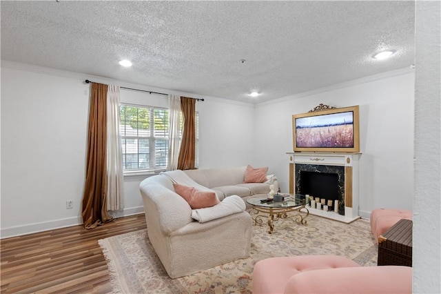 living area with a textured ceiling, wood finished floors, crown molding, recessed lighting, and a premium fireplace