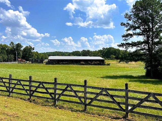 view of gate with fence, a yard, and a rural view