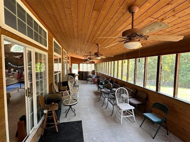 unfurnished sunroom featuring ceiling fan, wood ceiling, and plenty of natural light