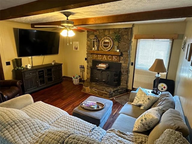 living room with a textured ceiling, beamed ceiling, a fireplace, hardwood / wood-style floors, and ceiling fan