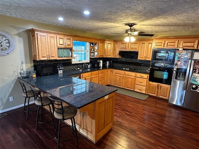 kitchen with a peninsula, tasteful backsplash, black appliances, and ceiling fan