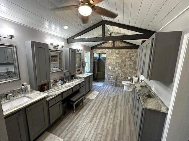 bathroom with lofted ceiling with beams, hardwood / wood-style floors, toilet, ceiling fan, and vanity