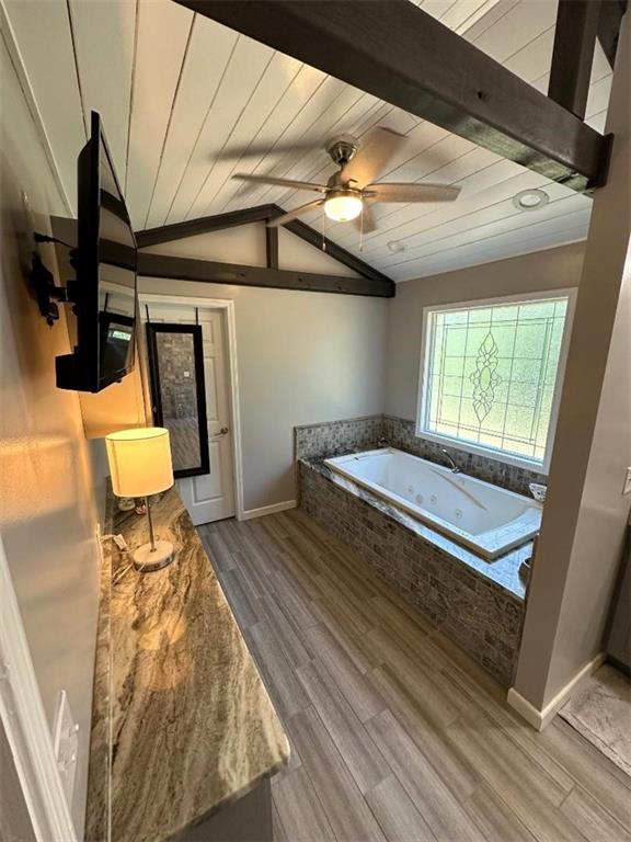 bathroom featuring vaulted ceiling with beams, hardwood / wood-style floors, ceiling fan, and tiled bath