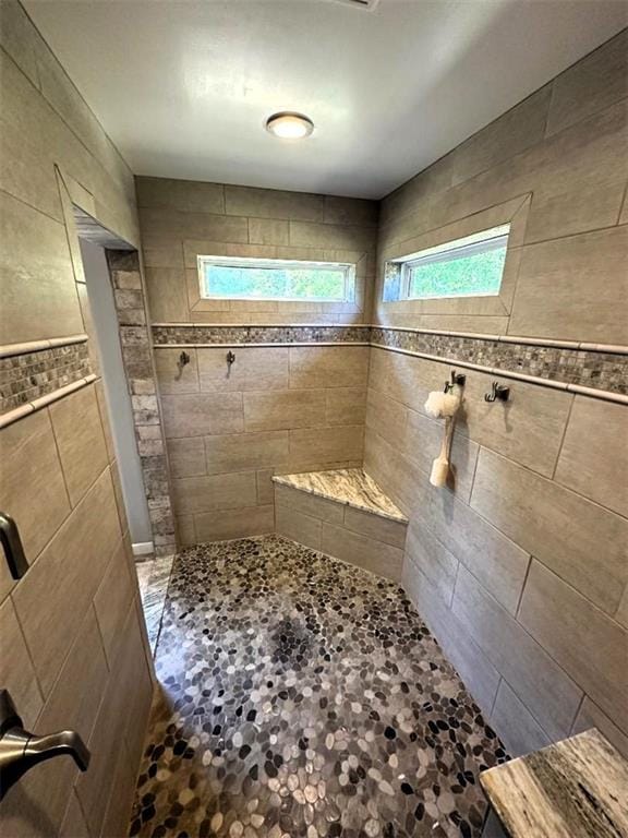full bath with tiled shower and tile walls