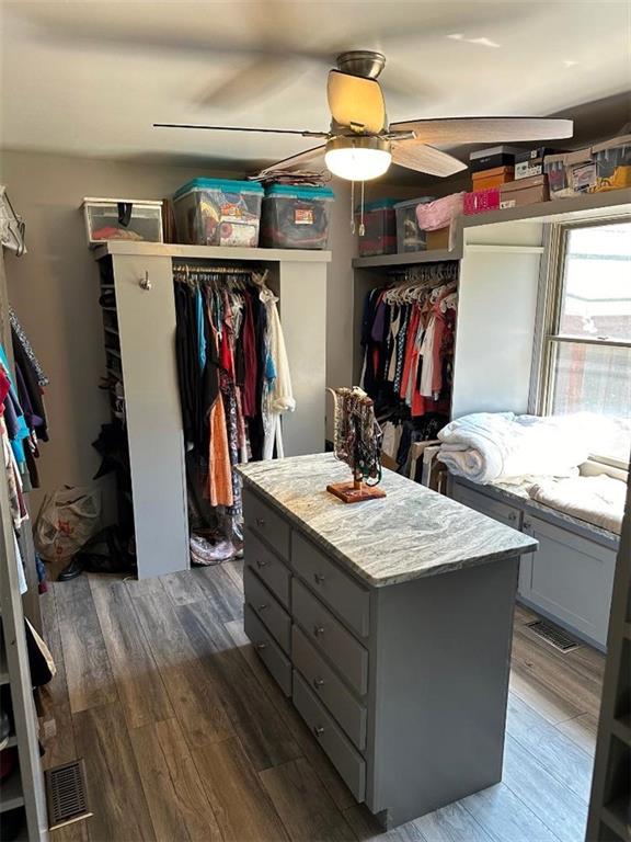 spacious closet with wood finished floors, visible vents, and a ceiling fan