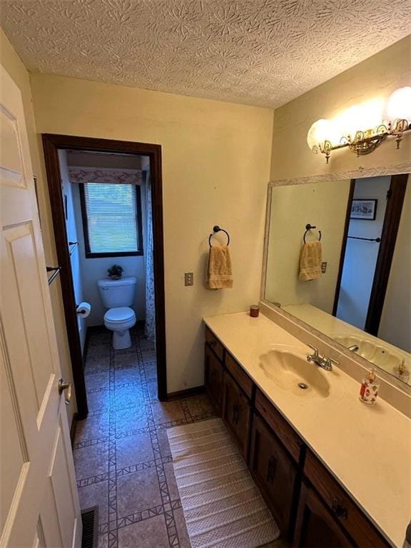 bathroom with tile patterned floors, a textured ceiling, vanity, toilet, and visible vents