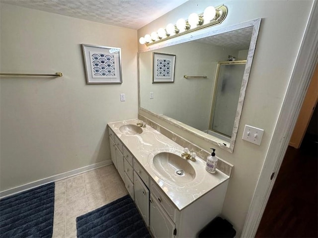 bathroom with tile patterned flooring, a sink, a textured ceiling, and double vanity