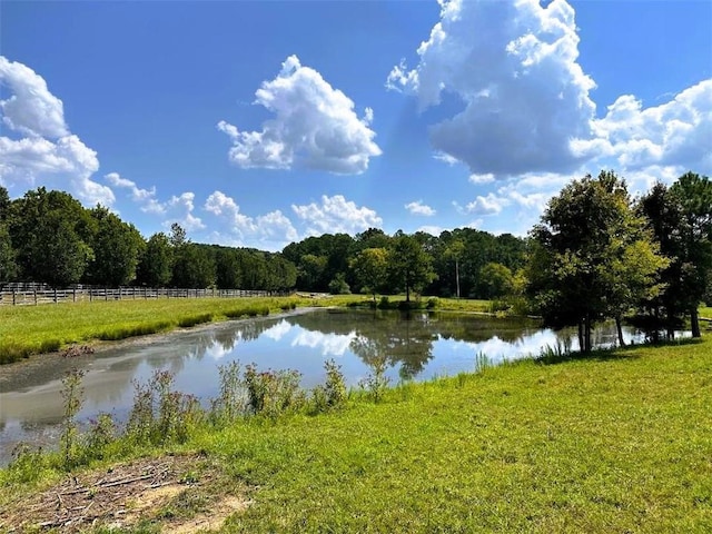 water view with fence and a view of trees