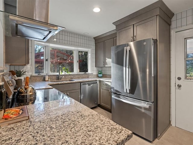 kitchen with light stone counters, sink, stainless steel appliances, and extractor fan