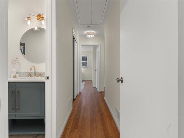 corridor with dark hardwood / wood-style flooring and sink