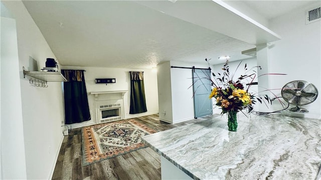 interior space with a barn door, visible vents, baseboards, and wood finished floors