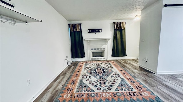 living area with a fireplace, a textured ceiling, a barn door, wood finished floors, and baseboards