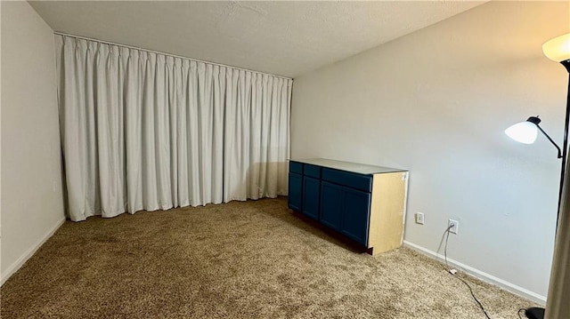 unfurnished room with baseboards and light colored carpet