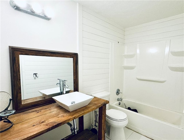 full bathroom featuring wooden walls, a sink, and toilet