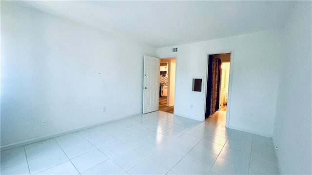 empty room featuring visible vents, baseboards, and light tile patterned floors