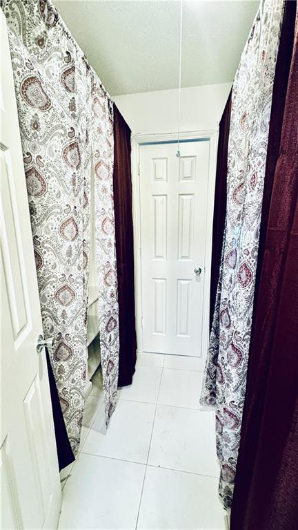 hall featuring tile patterned flooring and a textured ceiling