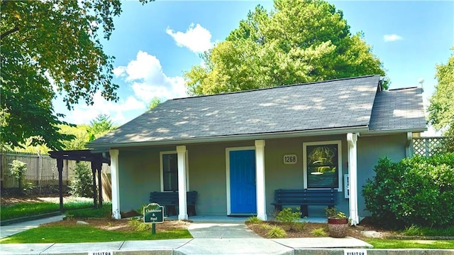 view of front of property with a porch, stucco siding, and fence