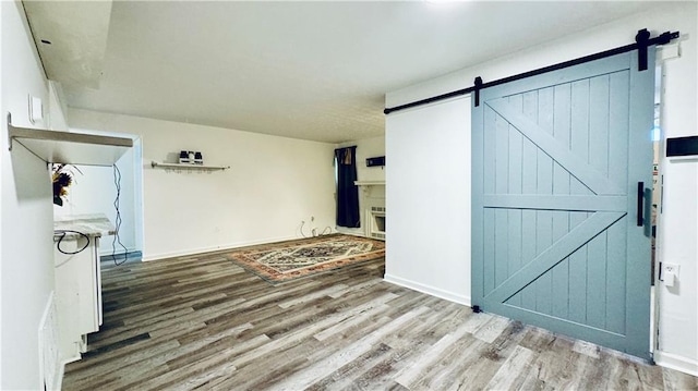 interior space featuring baseboards, a barn door, and wood finished floors