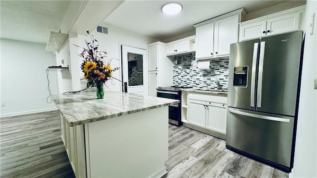 kitchen with visible vents, light wood-style floors, white cabinetry, stainless steel appliances, and decorative backsplash