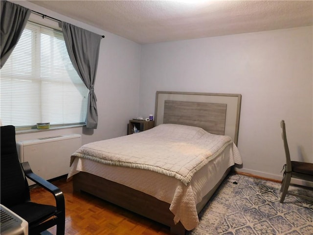 bedroom with a textured ceiling and parquet floors