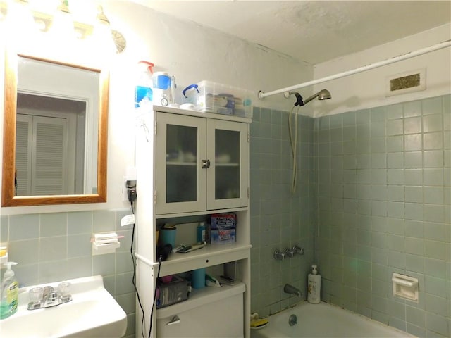 full bathroom featuring tile walls, toilet, sink, and tiled shower / bath