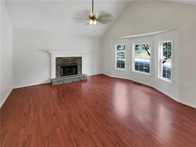 unfurnished living room featuring lofted ceiling, ceiling fan, dark hardwood / wood-style floors, and a stone fireplace