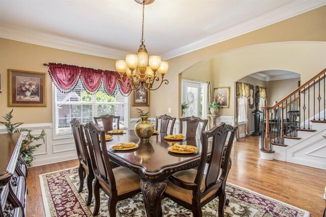 dining room with an inviting chandelier, wood-type flooring, and ornamental molding