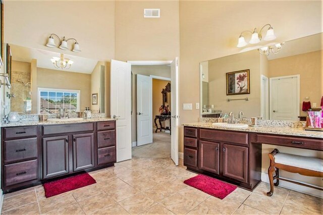 bathroom featuring tile patterned floors, vanity, a towering ceiling, and an inviting chandelier