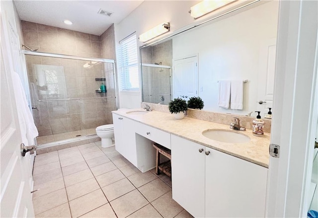 bathroom with tile patterned flooring, vanity, toilet, and an enclosed shower