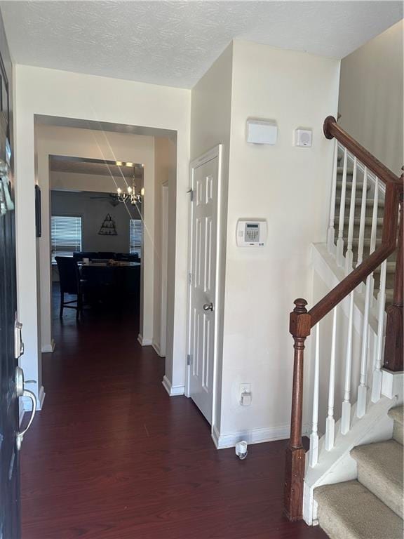 foyer with dark wood finished floors, a textured ceiling, baseboards, and stairs