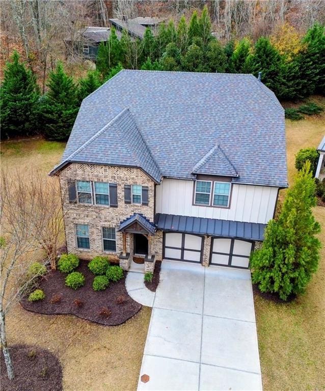 view of front of home with driveway, stone siding, an attached garage, and board and batten siding