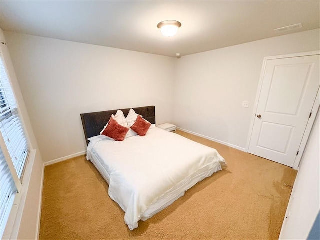 bedroom with light carpet, visible vents, and baseboards