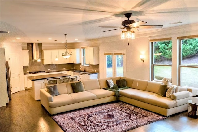 living room featuring a ceiling fan, wood finished floors, visible vents, and crown molding