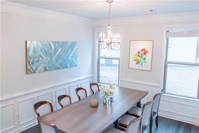 dining space with a wainscoted wall, a notable chandelier, visible vents, a decorative wall, and ornamental molding