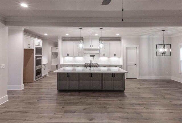 kitchen featuring pendant lighting, white cabinets, and an island with sink