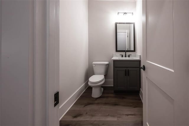 bathroom with toilet, vanity, and hardwood / wood-style flooring