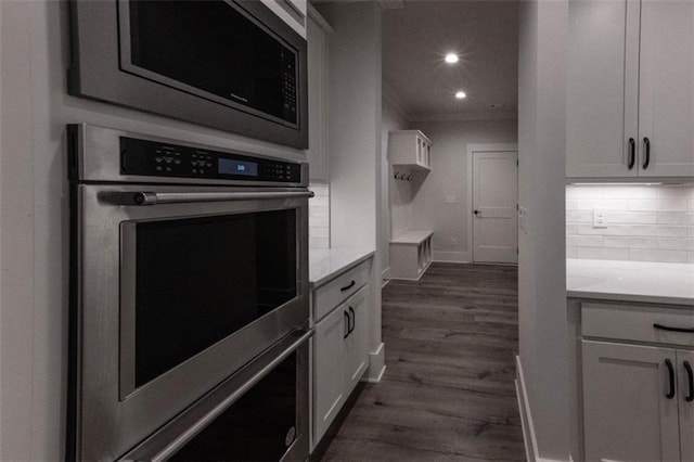 kitchen featuring dark hardwood / wood-style floors, appliances with stainless steel finishes, backsplash, and white cabinetry