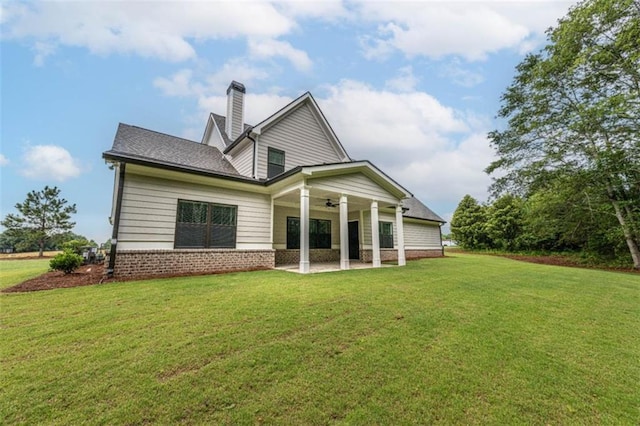 rear view of property with ceiling fan, a patio area, and a yard