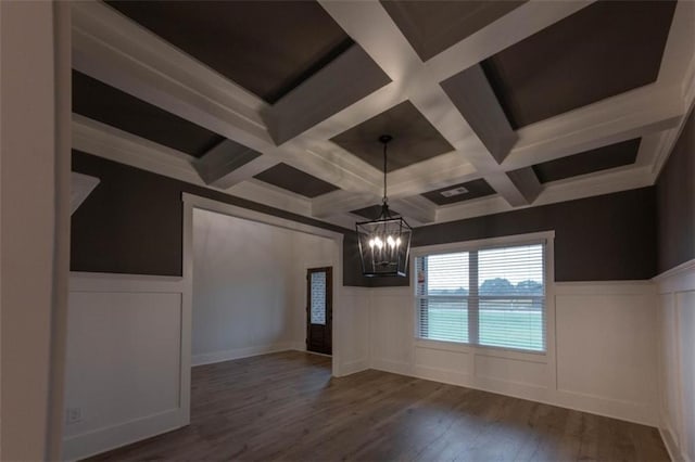 unfurnished living room featuring dark hardwood / wood-style floors, coffered ceiling, and a notable chandelier