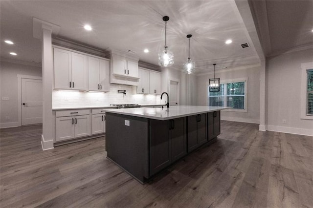 kitchen featuring white cabinetry, a large island with sink, dark hardwood / wood-style flooring, and decorative light fixtures