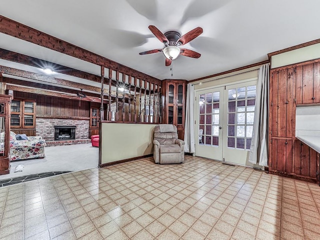 unfurnished room featuring a brick fireplace, beam ceiling, french doors, and ceiling fan