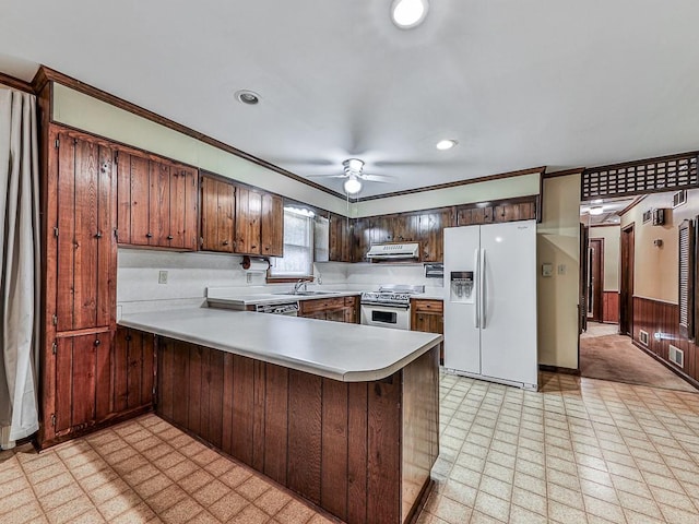 kitchen featuring sink, stainless steel stove, ceiling fan, white refrigerator with ice dispenser, and kitchen peninsula