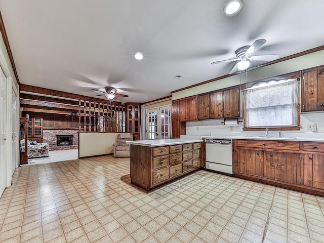 kitchen featuring sink, a brick fireplace, dishwasher, kitchen peninsula, and ceiling fan