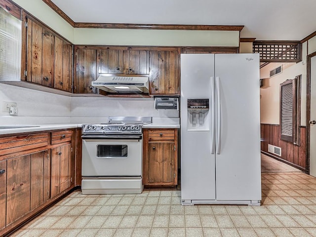 kitchen with crown molding, sink, white appliances, and wood walls